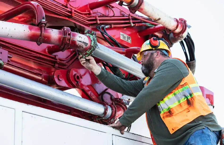Detailed view of bucket truck hydraulic lines and boom connection points being inspected for safety compliance
