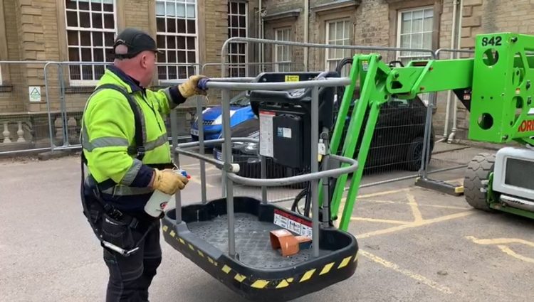 Operator checking aerial lift outrigger placement and ground stability before a cherry picker rental lift